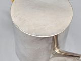 a silver tea pot with a yellow handle and a yellow handle