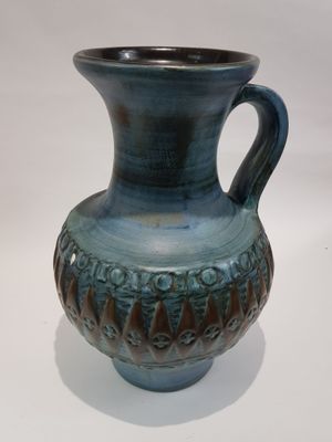 un vase bleu posé sur une surface blanche