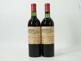 two bottles of red wine sitting next to each other on a white surface