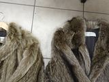 two coats of fur on a hanger in a store