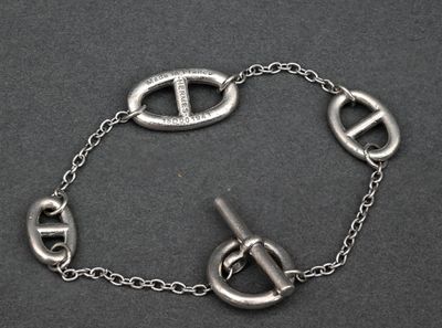 silver bracelet with a clasp on a chain on a black surface