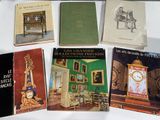 several books on a table with a clock in the middle of them