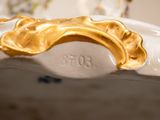 a close up of a gold and white vase on a table