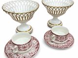 two red and white dishes with gold rims and saucers