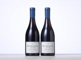 two bottles of red wine sitting on top of a table