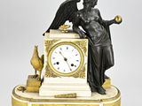 une statue représentant un ange tenant une horloge, posée sur une table