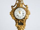 a gold clock hanging from the side of a wall
