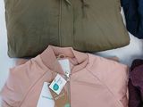 three jackets and a sweater are sitting on a white surface