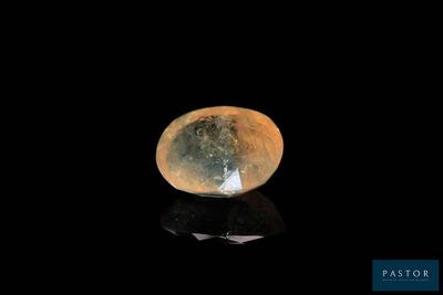 un gros plan d'un diamant sur une surface noire, avec la lune en arrière-plan