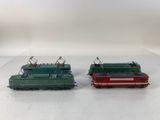 two green and red trains sitting side by side on a white surface