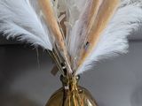 a gold vase with some white feathers in it