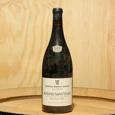 a bottle of wine sitting on top of a wooden barrel