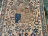 an antique rug with a woman and a bird on it