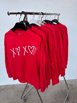 three red shirts are hanging on a rack in front of a white wall