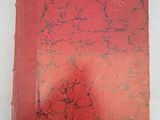 un vieux livre à la couverture rouge posé sur une table