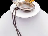 a white necklace with a gold pocket watch on it