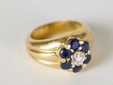 bague en or jaune sertie de saphirs bleus et de diamants sur un fond blanc