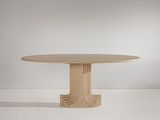 une table à manger ronde avec un piètement en bois dans une pièce blanche