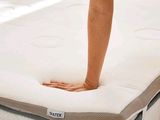 a woman standing on top of a mattress in a room