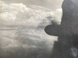 a black and white photo of a man standing on the beach