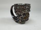 a silver cup with a design on it on a white surface