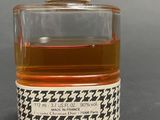 an image of a bottle of perfume with a hounds pattern on it