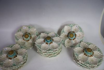 quatre fleurs en céramique blanches et vertes sont posées sur une surface blanche