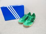 green and black adidas sneakers next to a blue box on a white surface