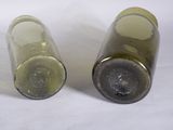 two empty wine bottles sitting next to each other on a white surface