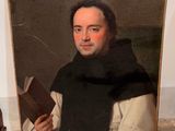 portrait of a man holding a book in front of a painting