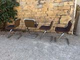three brown chairs sitting in front of a brick wall next to a plant