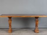 une vieille table en bois avec deux pieds tournés et un plateau en bois