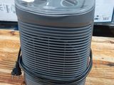 un purificateur d'air posé sur une table en bois, à côté d'une pile de cartons