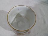 une tasse blanche à bord doré posée sur une table