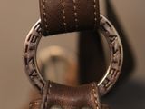 leather handbag with a metal ring hanging from it ' s side