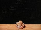 peinture représentant un bol de noix posé sur une table en bois, sur fond noir