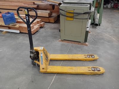 un chariot élévateur jaune garé dans un entrepôt rempli de bois