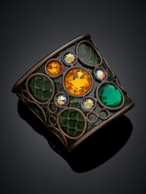 une image représentant une broche « broochle » verte et jaune posée sur une surface noire