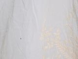 a white dress with gold embroidery on it on a bed