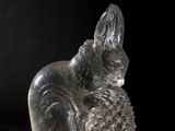 a glass figurine of a squirrel holding a pine cone