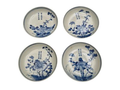 four blue and white plates with flowers on them on a white surface