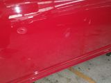 a close up of a red car with a broken door handle