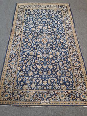 un tapis bleu bordé d'or posé sur un sol gris