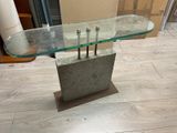 a glass table with a metal base on a wooden floor