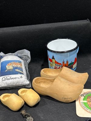 des sabots en bois, une chope, une paire de chaussures, un sac de farine et une clé sont posés sur une surface noire