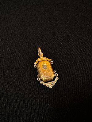 un gros plan d'un petit pendentif en or posé sur un tissu noir