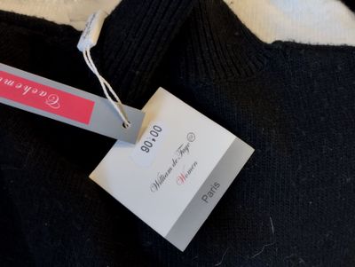 un pull noir avec une étiquette rose dessus