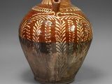 un vase marron et blanc posé sur une surface grise