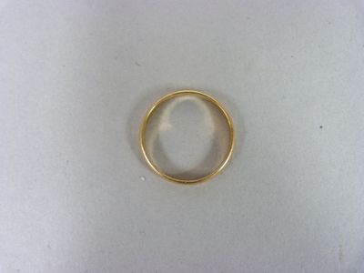 une bague en or posée sur une surface blanche, sur fond blanc