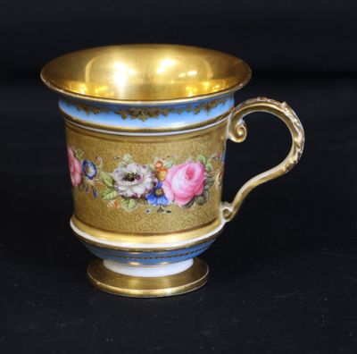 a gold cup with blue and pink flowers on it
